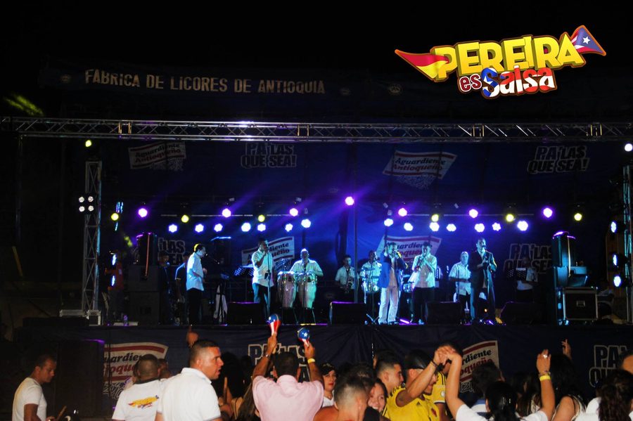 Escenario iluminado en azul con multitud en primer plano - Pereira es Salsa
