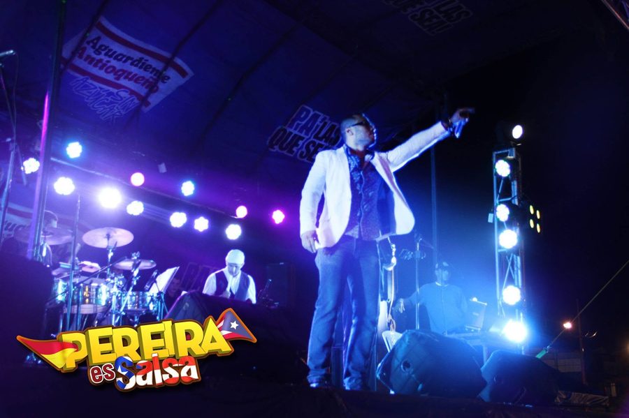 Vocalista bajo reflector azul junto a la orquesta - Pereira es Salsa